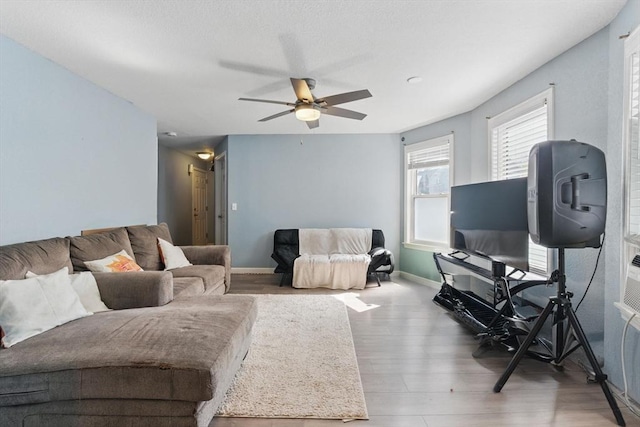 living room featuring baseboards, ceiling fan, and wood finished floors