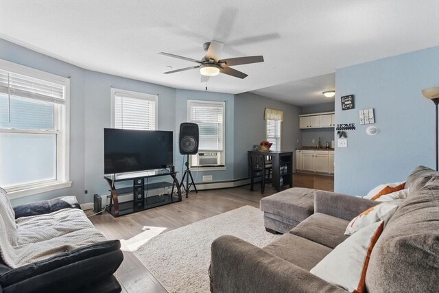 living area featuring ceiling fan, plenty of natural light, baseboards, and light wood finished floors