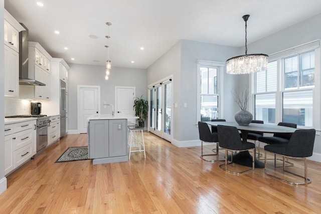 kitchen with white cabinetry, a kitchen breakfast bar, a kitchen island with sink, and hanging light fixtures