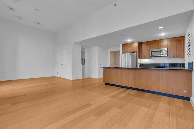 kitchen with light wood-type flooring, appliances with stainless steel finishes, and kitchen peninsula