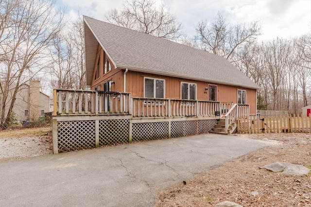 view of front facade with a shingled roof, a deck, and aphalt driveway