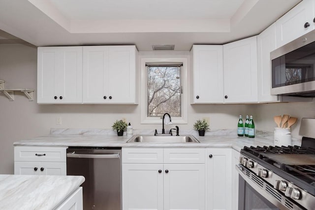 kitchen featuring appliances with stainless steel finishes, a tray ceiling, visible vents, and a sink