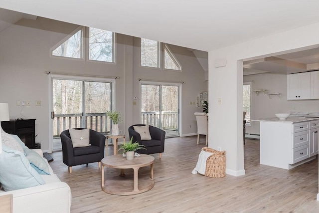 living room with light wood-type flooring, a baseboard radiator, and baseboards