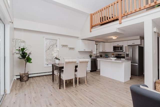 dining area with light wood-style floors, a baseboard heating unit, and high vaulted ceiling