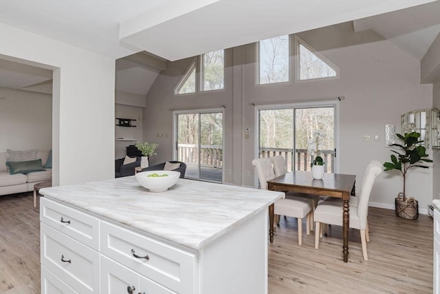 kitchen with baseboards, white cabinets, light wood finished floors, and light stone countertops