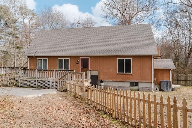 back of house with a shingled roof, fence, a wooden deck, and central AC unit