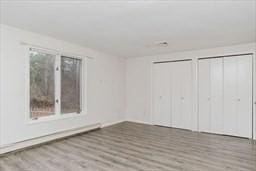 unfurnished bedroom with wood finished floors and multiple closets