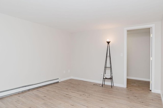 unfurnished room featuring a baseboard heating unit, baseboards, and light wood-style floors