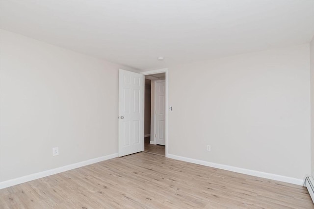 spare room with light wood finished floors, baseboards, and a baseboard heating unit