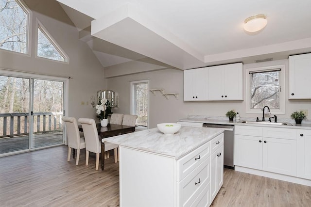 kitchen with light wood finished floors, white cabinetry, a kitchen island, a sink, and dishwasher