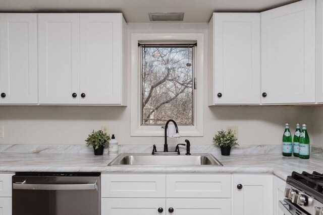 kitchen featuring stainless steel appliances, a sink, visible vents, and white cabinets