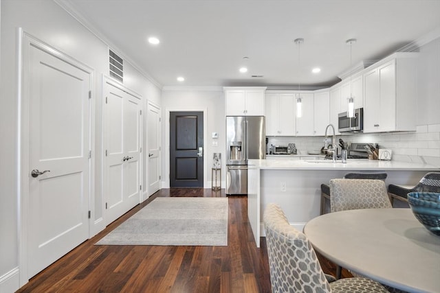 kitchen with pendant lighting, a breakfast bar area, stainless steel appliances, white cabinets, and kitchen peninsula