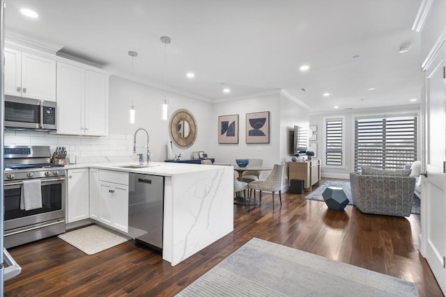 kitchen featuring hanging light fixtures, appliances with stainless steel finishes, sink, and white cabinets