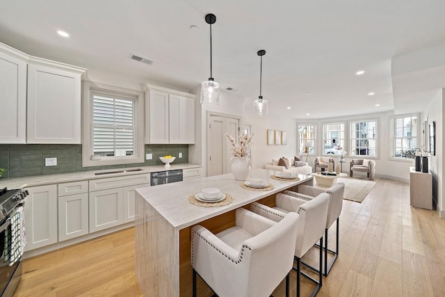 59 Falcon St Unit 1, Boston, MA 02128 - kitchen featuring stainless steel appliances, decorative backsplash, white cabinets, a kitchen island, and recessed lighting