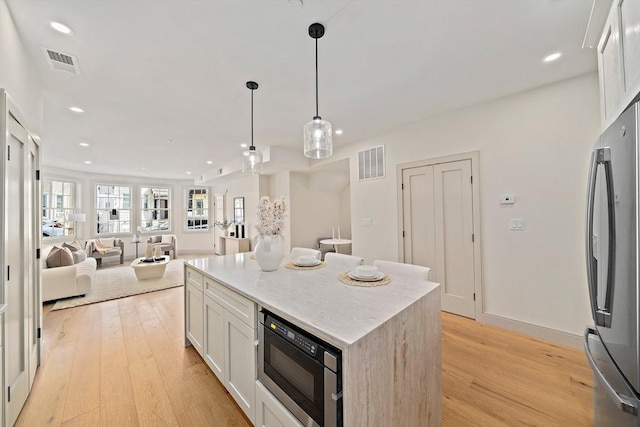 59 Falcon St Unit 1, Boston, MA 02128 - kitchen featuring appliances with stainless steel finishes, light wood-style flooring, recessed lighting, decorative light fixtures, and white cabinetry