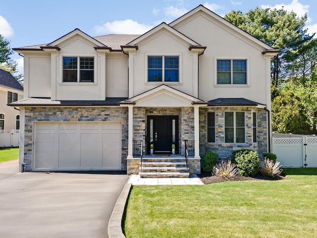 view of front facade featuring fence, stone siding, stucco siding, a front yard, and driveway