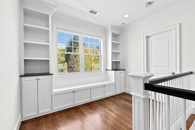 interior space featuring visible vents, ornamental molding, baseboards, and dark wood-style floors