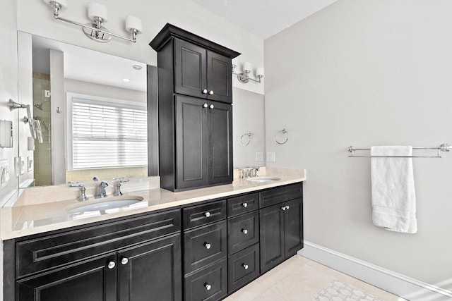 bathroom featuring double vanity, baseboards, tiled shower, and a sink
