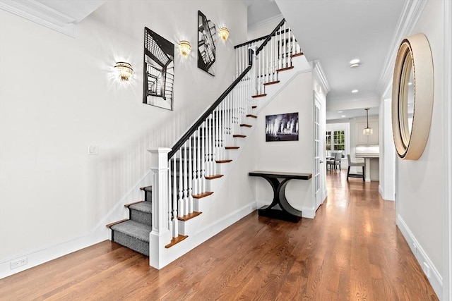stairway featuring baseboards, ornamental molding, wood finished floors, and recessed lighting