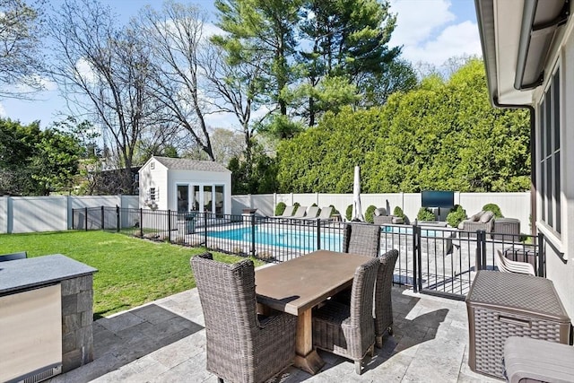 view of patio / terrace featuring a fenced in pool, a fenced backyard, an outbuilding, and outdoor dining area