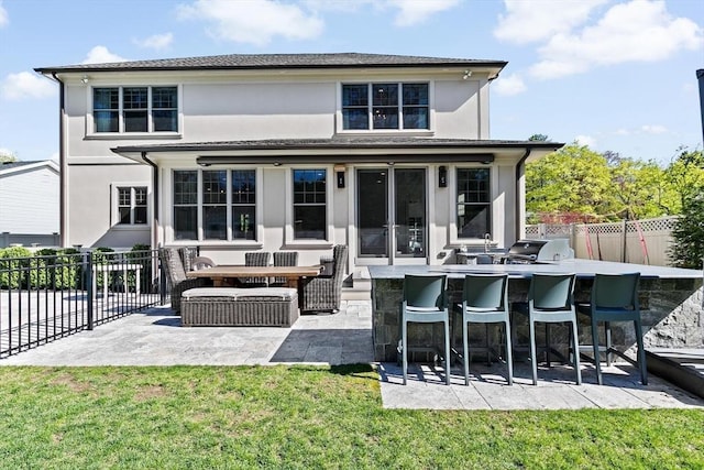 rear view of house featuring a patio, a fenced backyard, stucco siding, outdoor dry bar, and a yard
