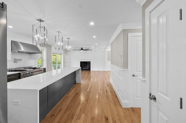 kitchen with pendant lighting, high end range, ornamental molding, a center island, and light hardwood / wood-style floors