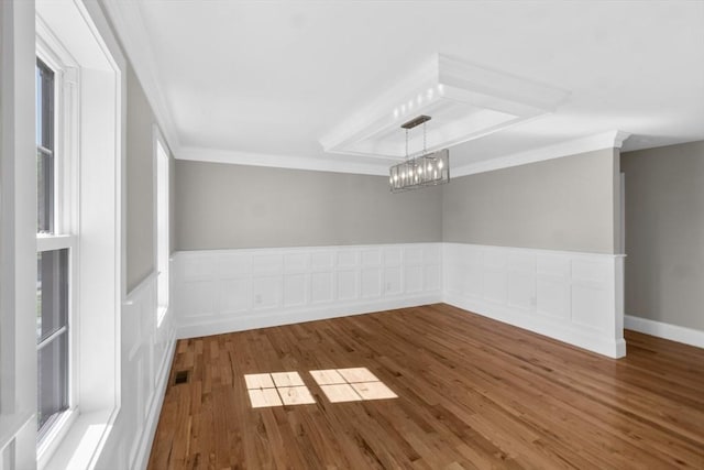 spare room with hardwood / wood-style flooring, crown molding, and a notable chandelier