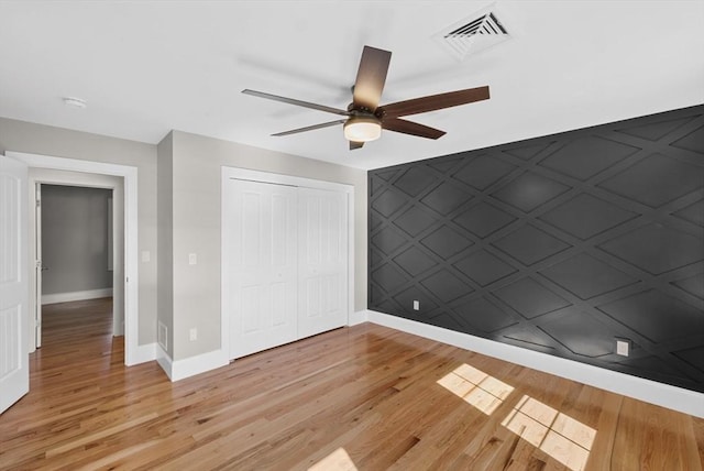 unfurnished bedroom with ceiling fan, a closet, and light hardwood / wood-style flooring