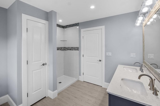 bathroom with a tile shower, vanity, and wood-type flooring