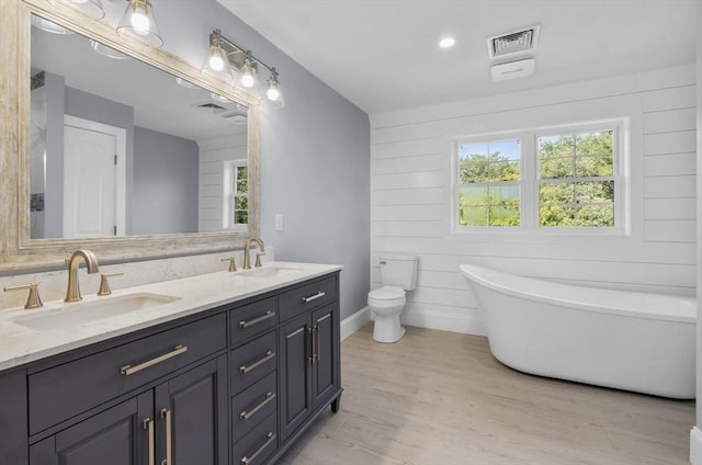 bathroom featuring a healthy amount of sunlight, hardwood / wood-style floors, vanity, and a bathtub