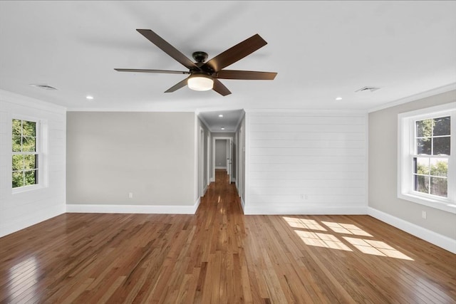 unfurnished living room with hardwood / wood-style flooring, ornamental molding, and a healthy amount of sunlight