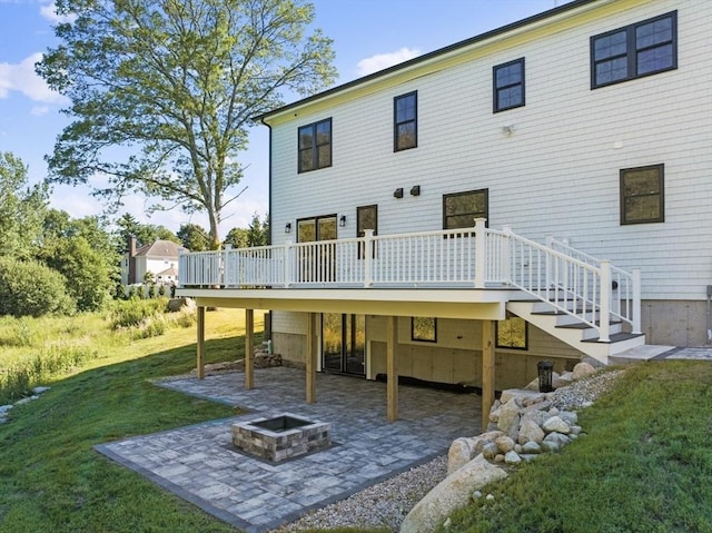 back of property featuring a yard, a deck, a patio, and an outdoor fire pit