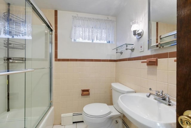 full bathroom with toilet, tile walls, a baseboard heating unit, combined bath / shower with glass door, and sink