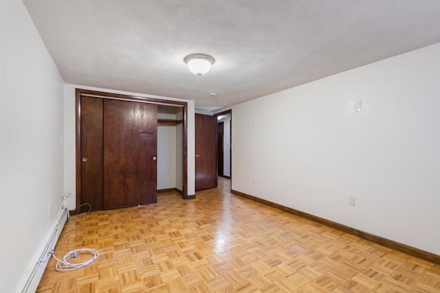 unfurnished bedroom with a baseboard heating unit, a closet, and light parquet floors