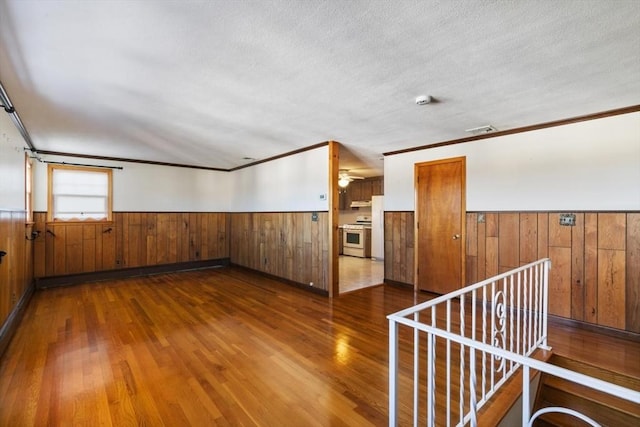 empty room featuring dark wood-type flooring, ornamental molding, and a textured ceiling