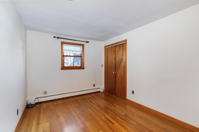 empty room with light hardwood / wood-style floors and a baseboard heating unit