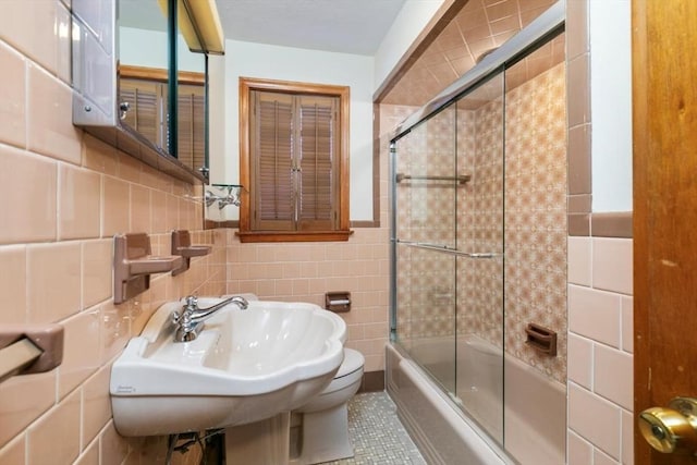 bathroom with sink, tile walls, tile patterned floors, and shower / bath combination with glass door