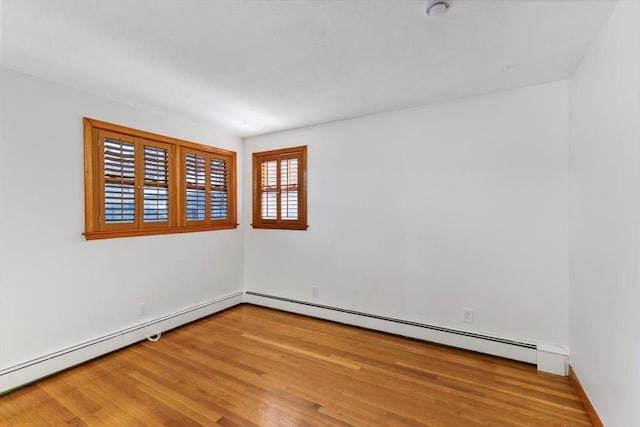 spare room with a baseboard heating unit and hardwood / wood-style flooring