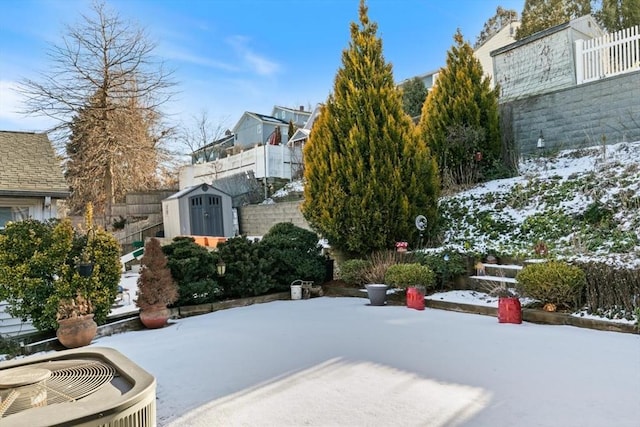 yard layered in snow with a storage unit and central air condition unit