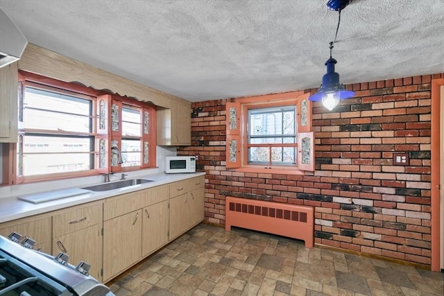 kitchen featuring brick wall, range, radiator, decorative light fixtures, and sink