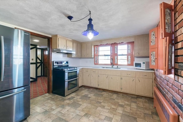 kitchen featuring decorative light fixtures, light brown cabinetry, appliances with stainless steel finishes, and sink