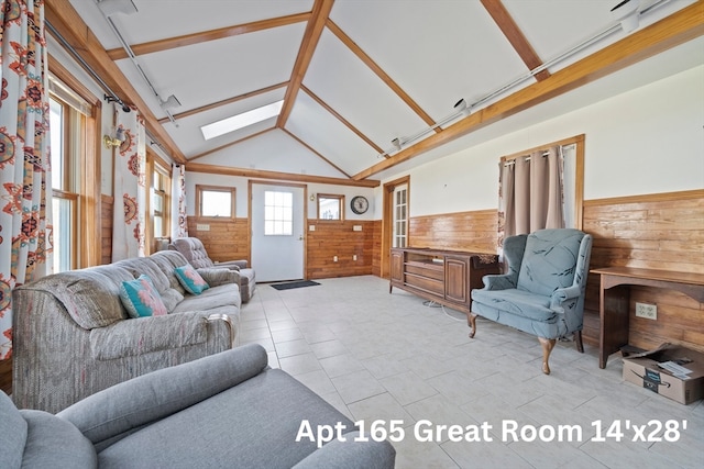 tiled living room featuring wood walls, high vaulted ceiling, and a skylight