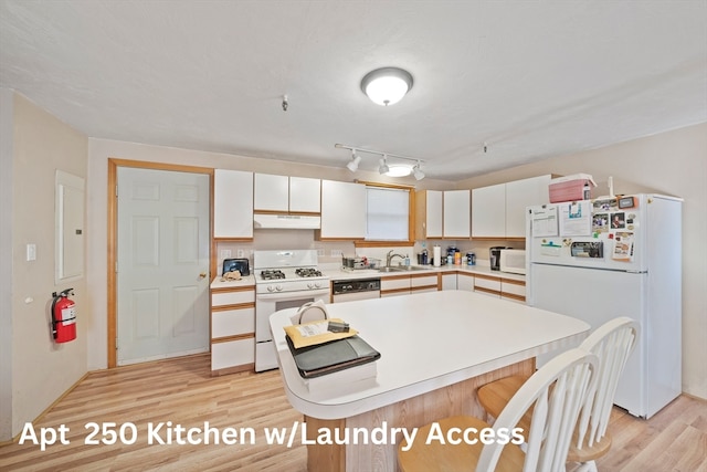 kitchen with white cabinets, light wood-type flooring, white appliances, and sink