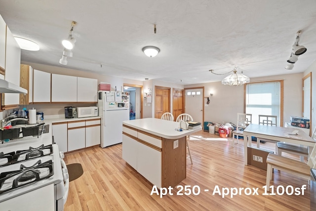 kitchen featuring a center island, white appliances, white cabinets, decorative light fixtures, and light hardwood / wood-style floors