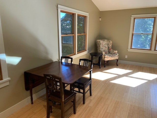 dining area featuring light wood-type flooring, vaulted ceiling, and plenty of natural light