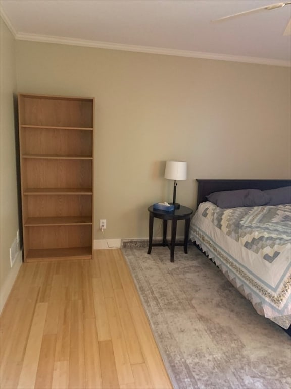 bedroom with crown molding, wood-type flooring, and ceiling fan