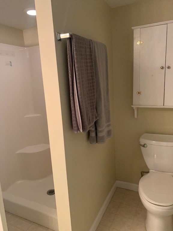 bathroom featuring toilet, walk in shower, and tile patterned floors