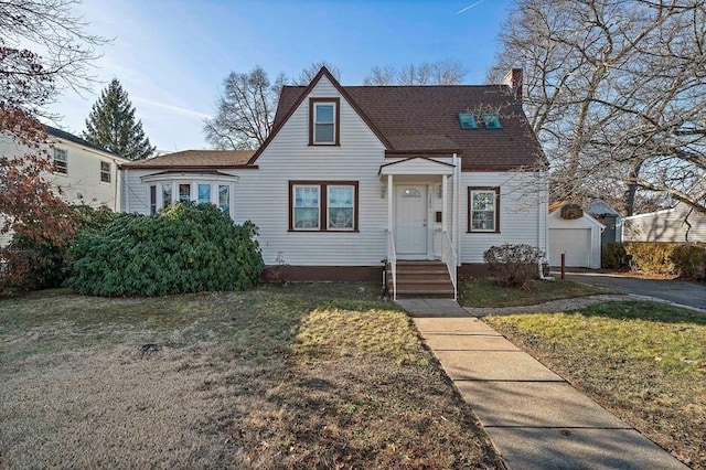 bungalow-style house with a garage, a front lawn, and an outdoor structure