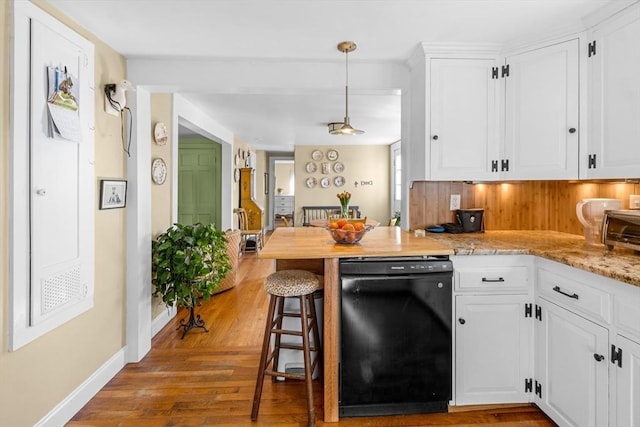 kitchen featuring light stone counters, wood finished floors, white cabinetry, black dishwasher, and hanging light fixtures