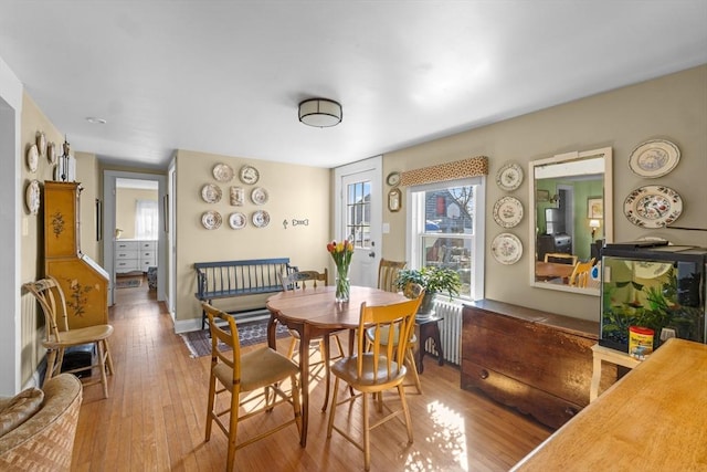 dining area with radiator heating unit, light wood-type flooring, and baseboards